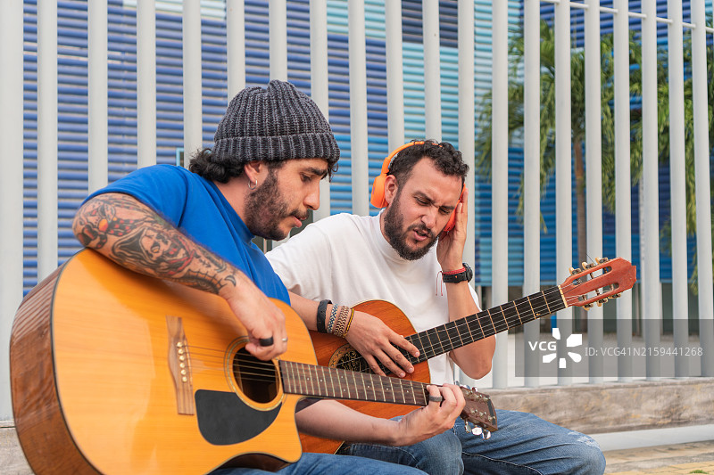 男老师和他的学生坐在凳子上在户外弹吉他图片素材