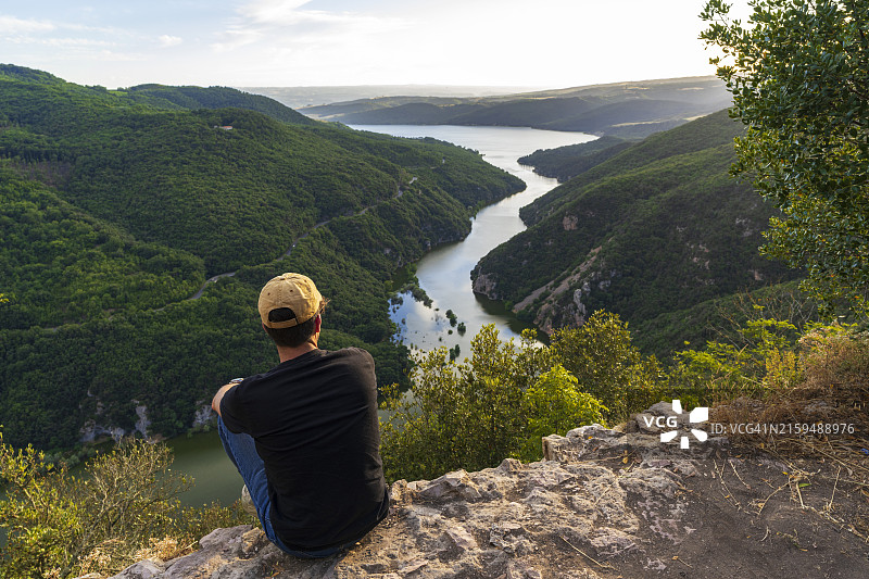 在岩石上欣赏峡谷河流美景的男人图片素材