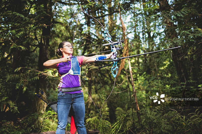 在美国华盛顿州贝尔费尔森林里拿着弓的日裔美国女孩图片素材