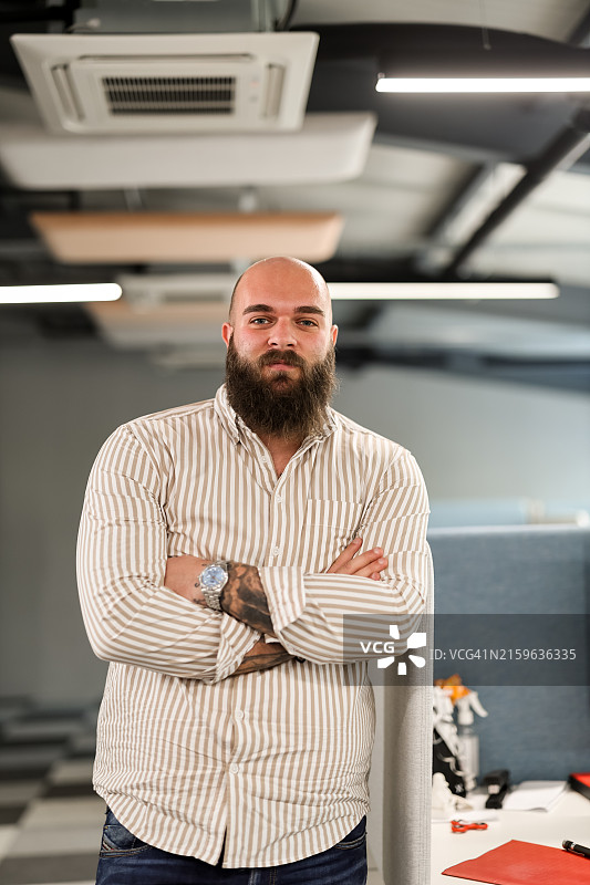 年轻商人 стоящий в современном офисе, скрестив руки图片素材