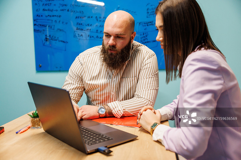 在办公室隔间一起工作的年轻同事图片素材