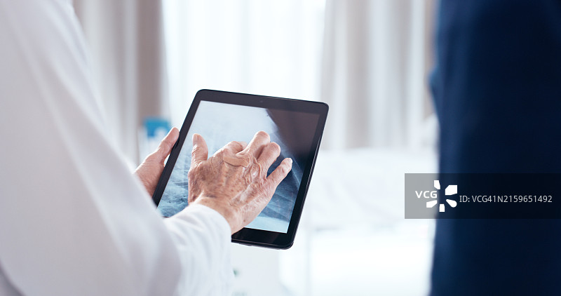 男女资深医生进行专业会诊，查看平板电脑上的医学图像图片素材