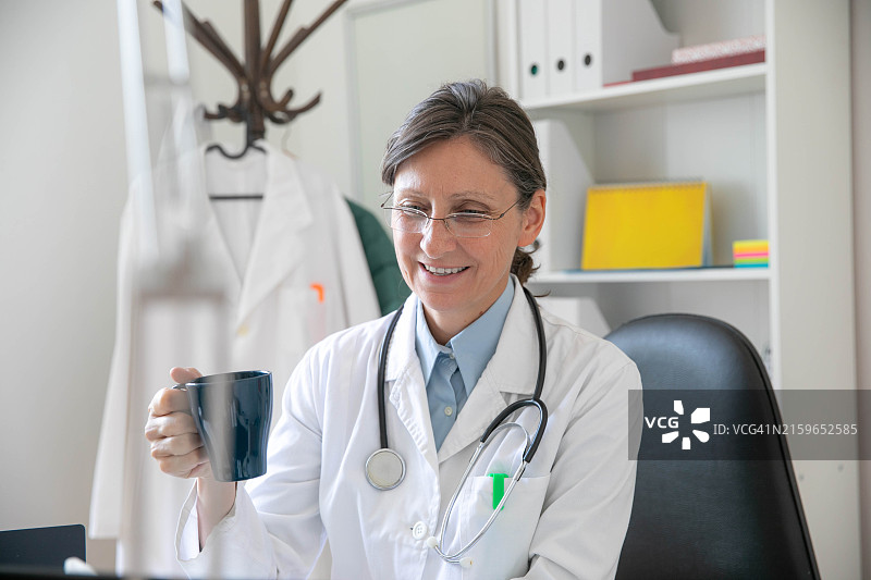 身穿商务装的反思中的年长女性手持咖啡杯图片素材