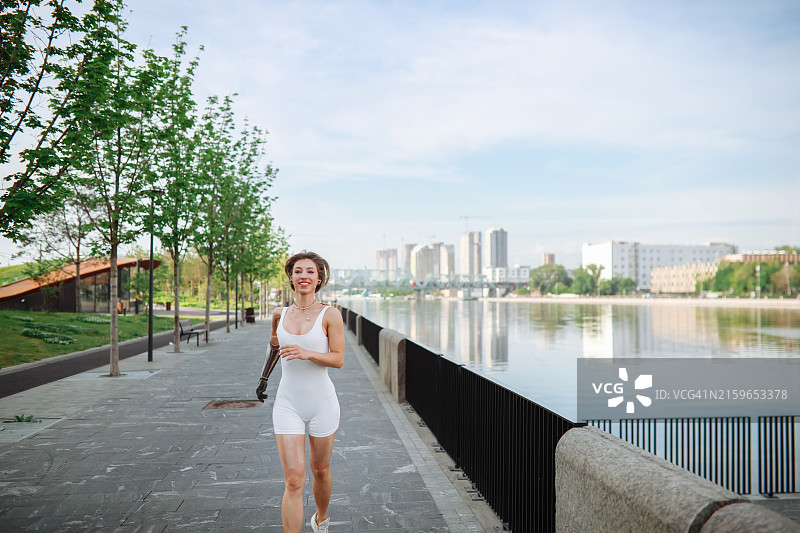 活力早晨：身材苗条的女性用假肢手臂沿着城市海滨慢跑图片素材