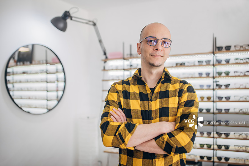 在眼镜店里穿着时尚格子衬衫的自信男人图片素材