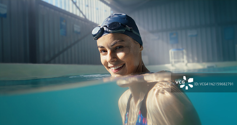 一位女性在游泳池里微笑的肖像，用于体育游泳训练、锻炼和比赛的实践表现。一位女运动员正在进行水上运动、心血管健康和铁人三项比赛图片素材