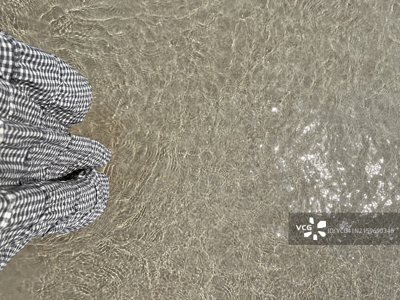 女子身穿格子裙在海滩浅水中漫步的主观视角图片素材