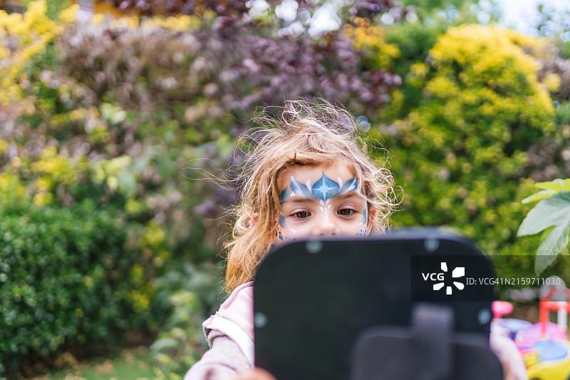 在花园里看平板电脑的彩绘女孩图片素材