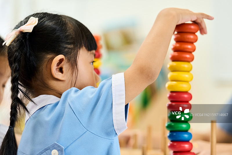 女学生在幼儿园堆叠彩色圆环图片素材