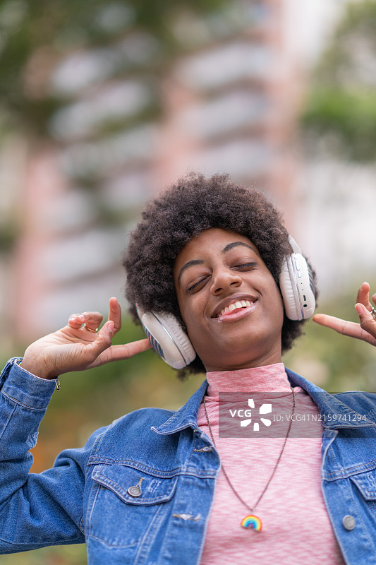在公园戴着耳机享受音乐的非裔美国妇女图片素材