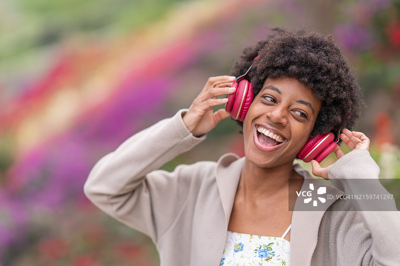戴着耳机在公园里听她最喜欢的歌曲的非裔美国妇女图片素材