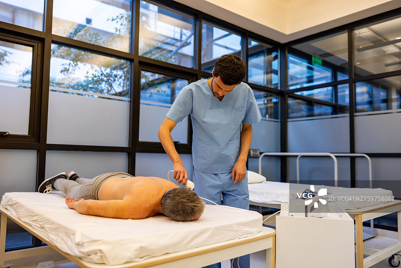 理疗师使用超声波刺激帮助男子康复图片素材