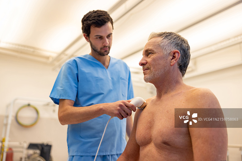 理疗中，男人接受肩部超声波刺激图片素材