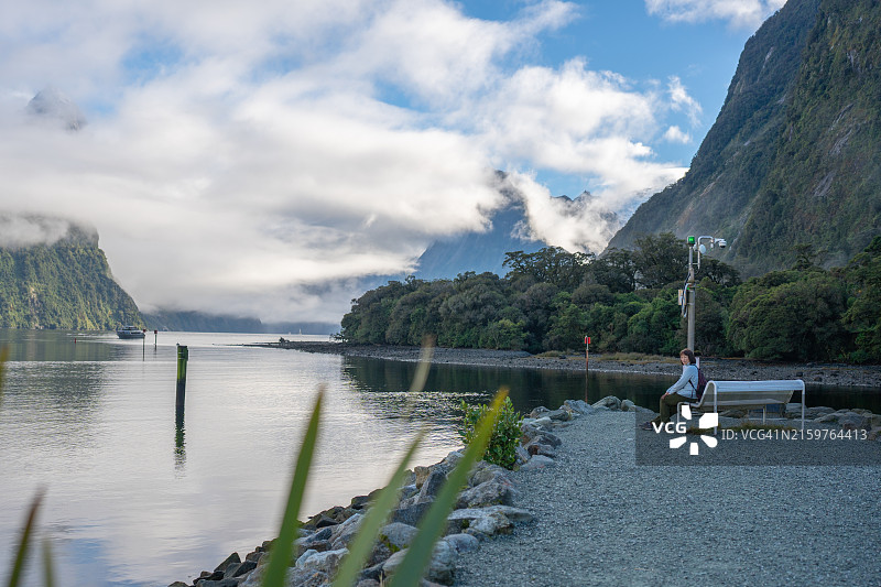 独自旅行的女人坐在河边长椅上图片素材