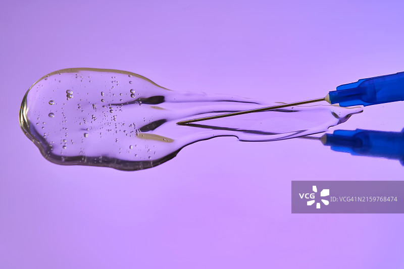 紫色背景上的注射器和流动的医用或化妆品图片素材