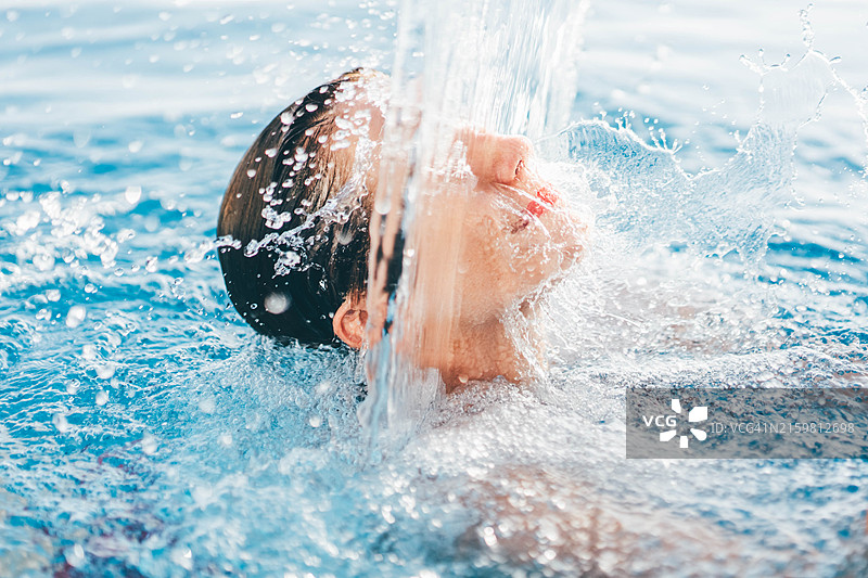 宁静的女人在瀑布下的水疗中心放松身心。女人在水力按摩池中放松。图片素材