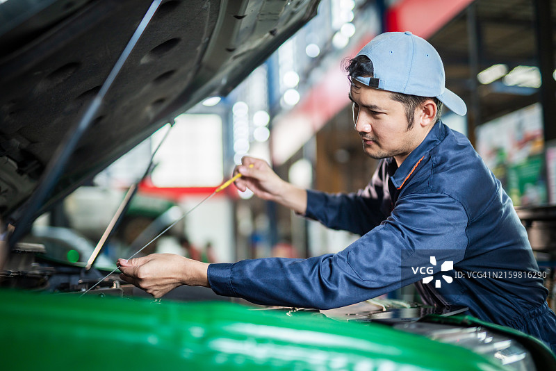亚洲男汽修工检查汽车发动机油位图片素材