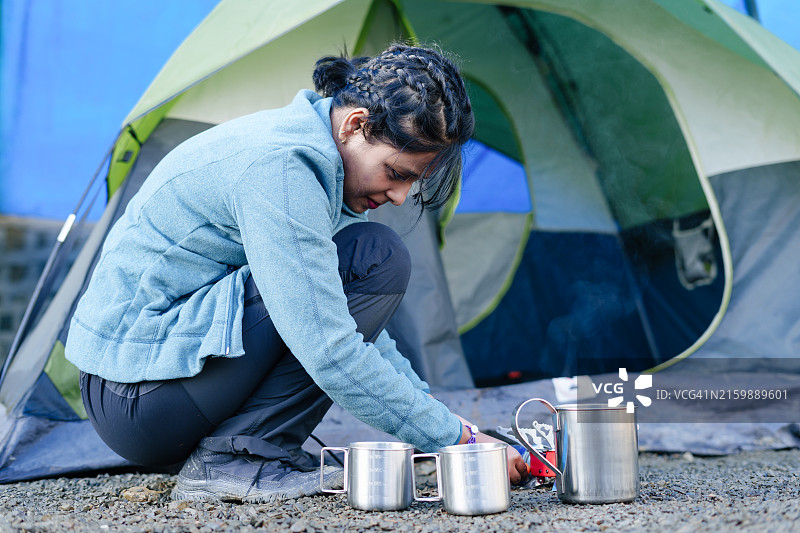 年轻女人在帐篷旁边点燃炉子图片素材