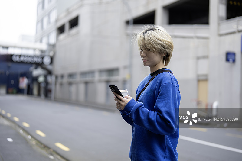 亚洲女人在都市背景下看手机图片素材