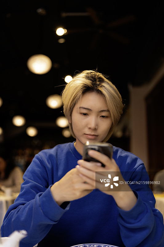 在餐厅专心使用智能手机的亚洲女人图片素材