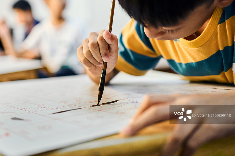 在学校教室里学习中国书法的男孩特写图片素材