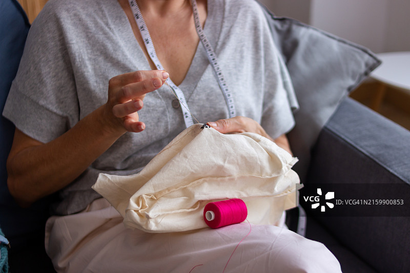 裁缝在白色面料上穿针引线图片素材