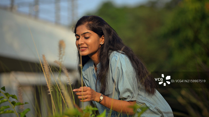 快乐的年轻女人高兴地玩耍，吹着草花图片素材
