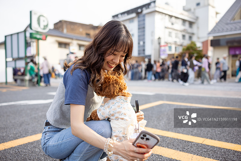 年轻女人在街上和玩具贵宾犬自拍图片素材