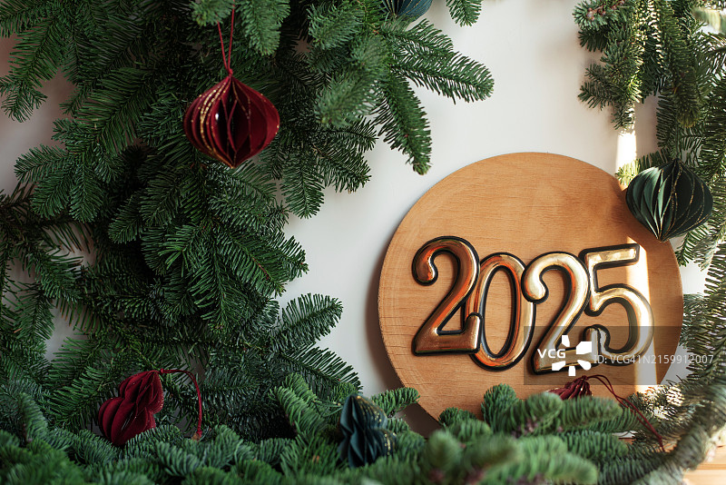 2025年新年圣诞节假日：带有圣诞树枝的纯色背景上的2025新年数字图片素材