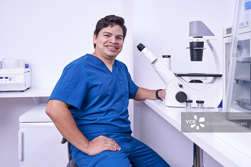 医生在植发诊所工作，准备用显微镜检查患者的毛囊，看着镜头图片素材