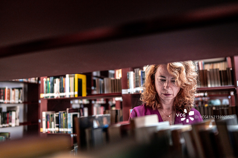 一个在图书馆找书的成熟的女人图片素材