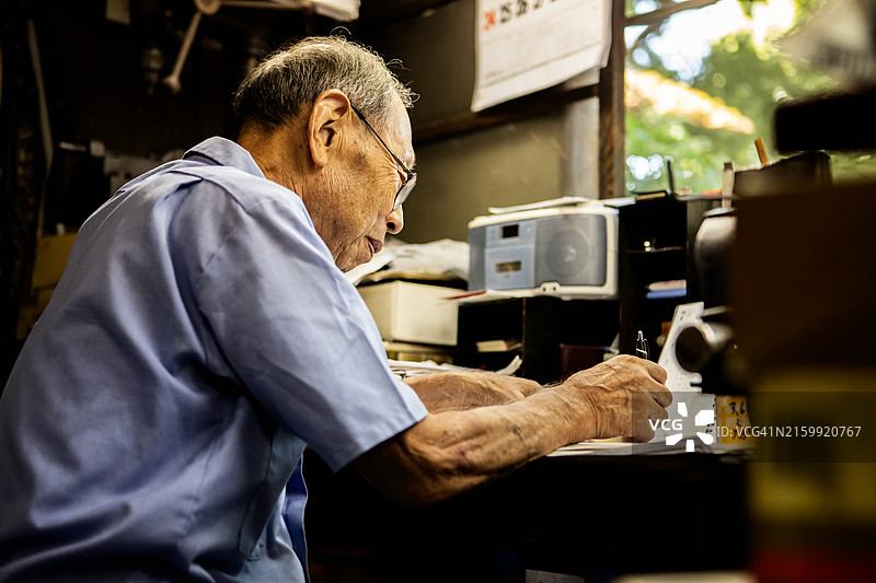 年长的工匠在市区的一家金属加工店工作图片素材