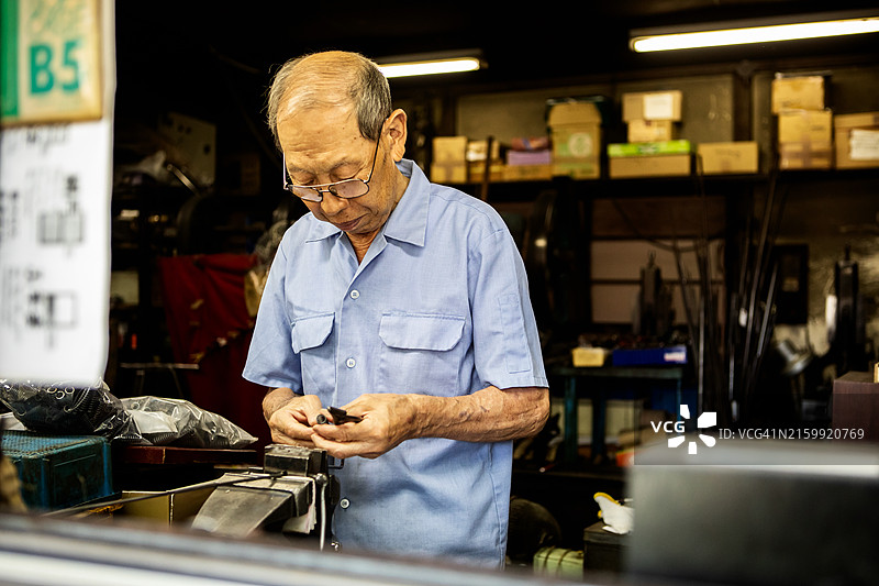 年长的工匠在市区的一家金属加工店工作图片素材