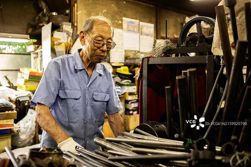 年长的工匠在市区的一家金属加工店工作图片素材
