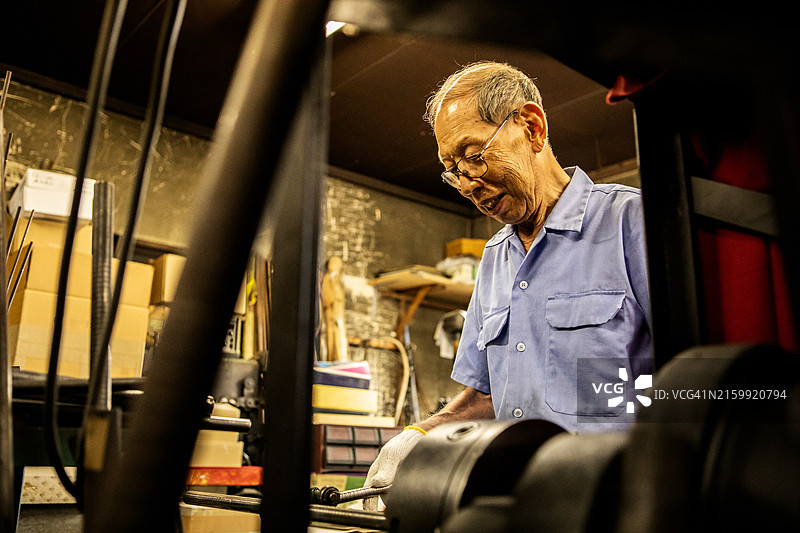 年长的工匠在市区的一家金属加工店工作图片素材
