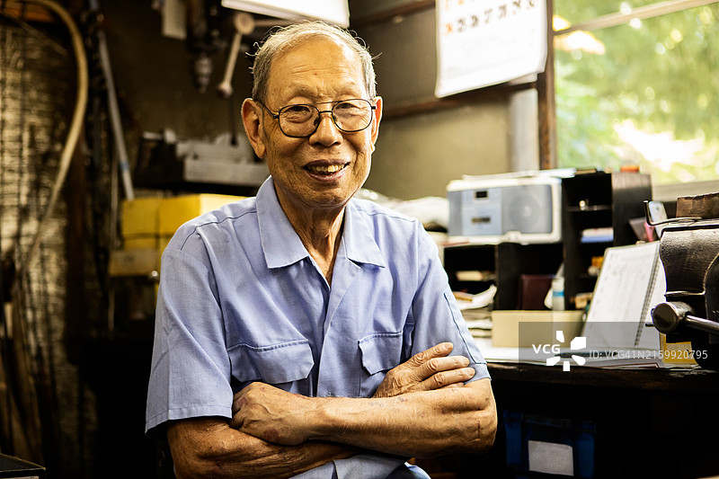 年长的工匠在市区的一家金属加工店工作图片素材