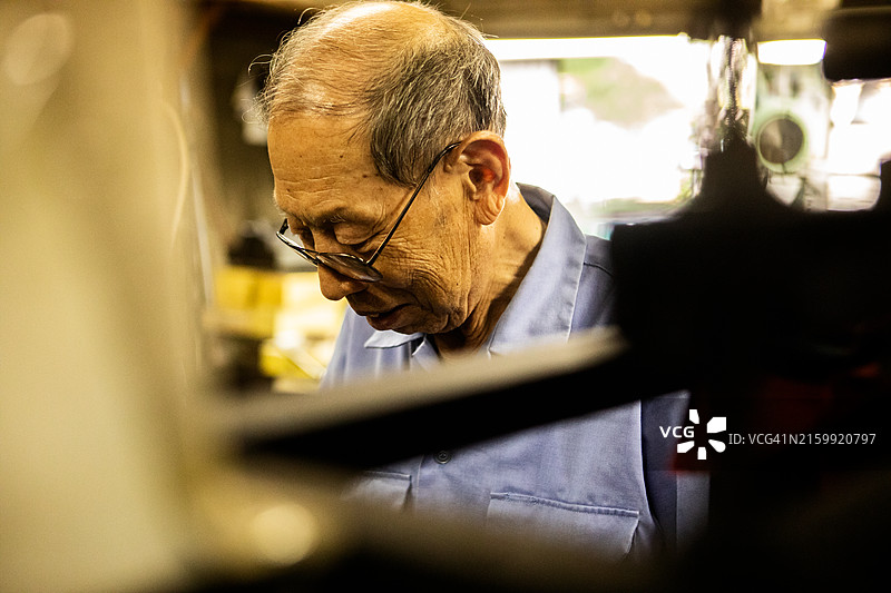 年长的工匠在市区的一家金属加工店工作图片素材