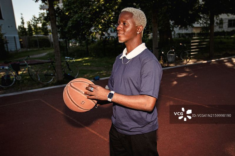 在户外打篮球的有色人种男子肖像。手持篮球的黑人男子照片。在公园里进行街头篮球运动的帅气人群的生活方式运动摄影。图片素材