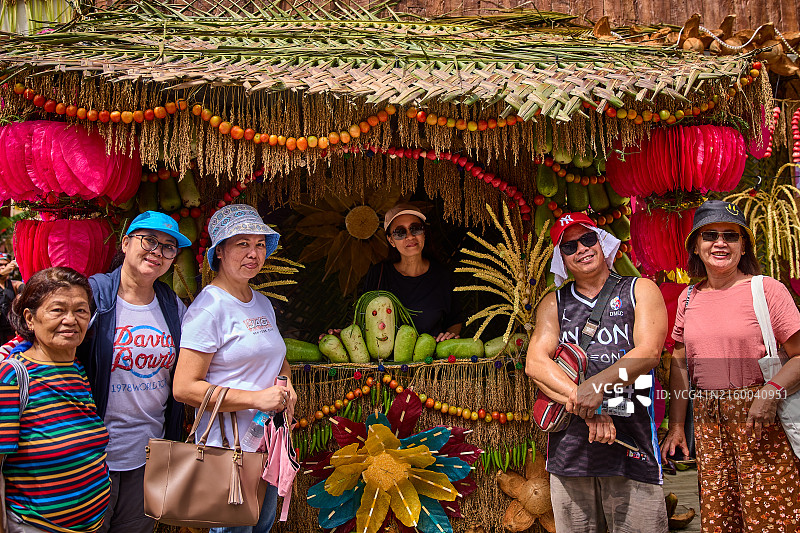 一群人在一个装饰着农业材料的展位上拍照。图片素材