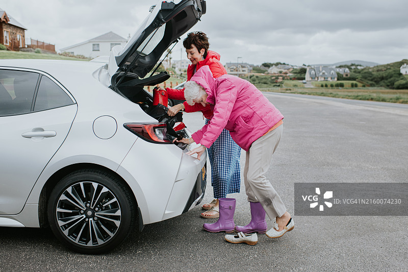 中年妇女和她年迈的母亲站在汽车旁，打开后备箱，取出惠灵顿靴图片素材
