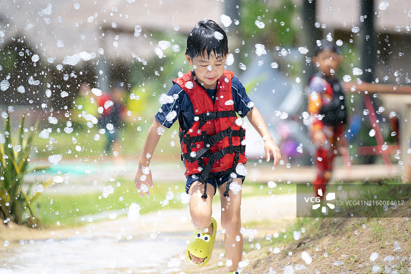 亚洲男孩穿着救生衣在充满泡泡的游乐园里玩耍图片素材