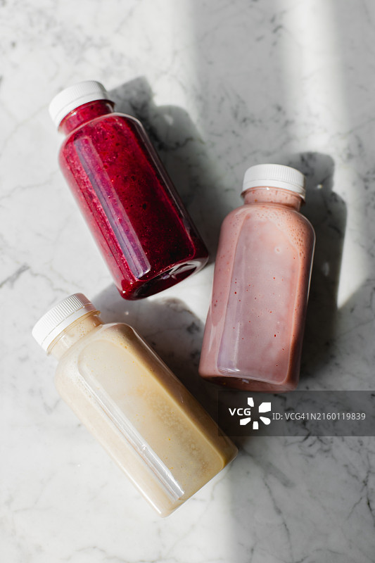大理石桌上生态塑料瓶装浆果水果冰沙饮品图片素材