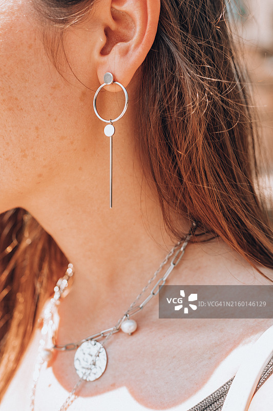 匿名女子佩戴的闪耀银饰项链和耳环图片素材