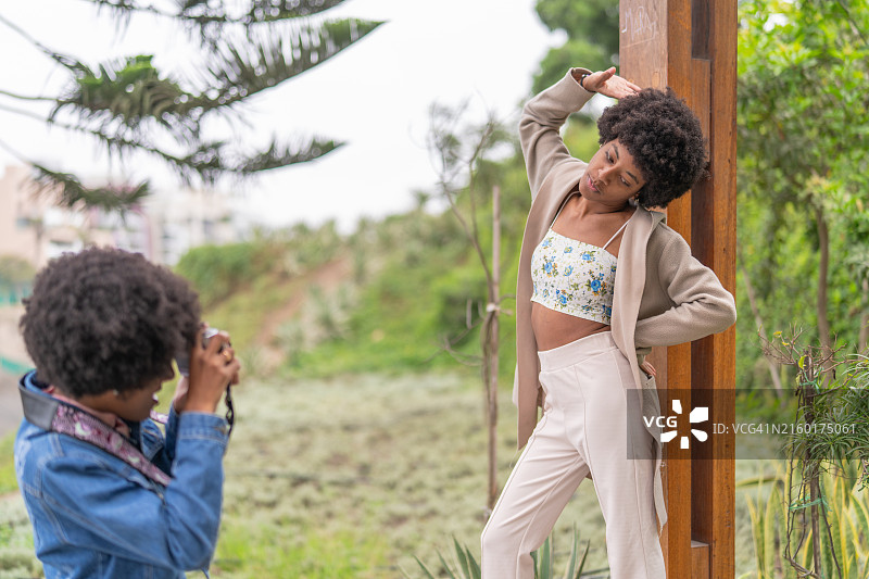 非裔美国女人在公园里摆姿势让她的双胞胎姐妹拍照图片素材