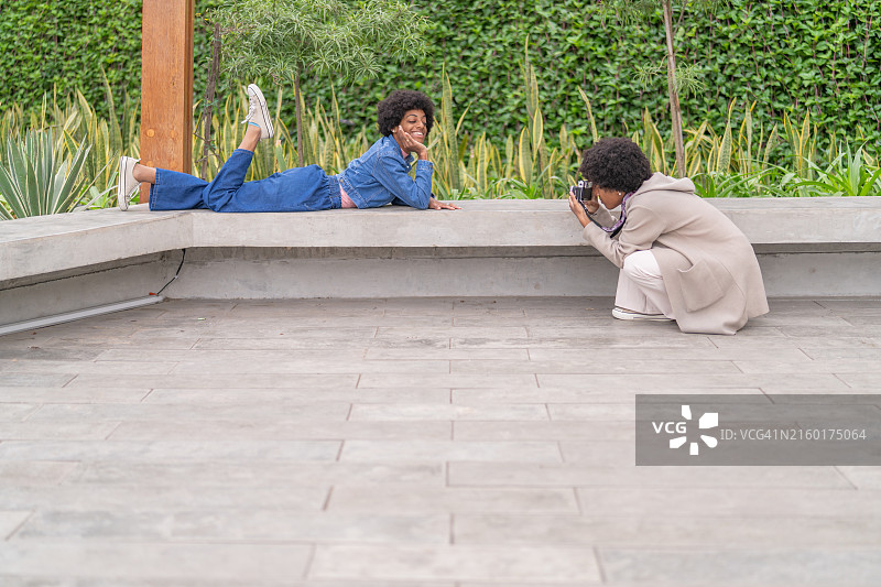 非裔美国女人在公园里摆姿势让她的妹妹拍照图片素材
