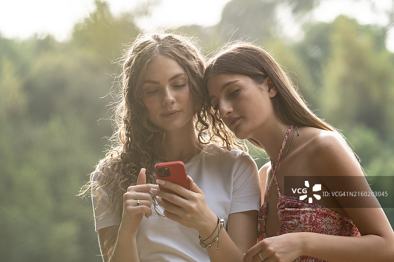 两个年轻女人在户外用智能手机和支付卡购物图片素材
