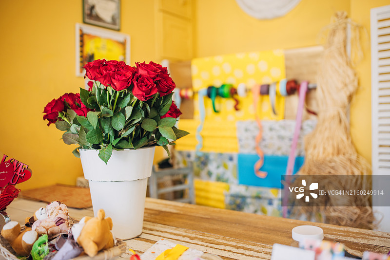 色彩缤纷礼品店装饰中的红玫瑰白色花瓶图片素材