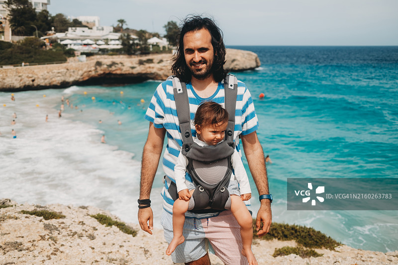 父亲背着宝宝在海滩上享受暑假图片素材