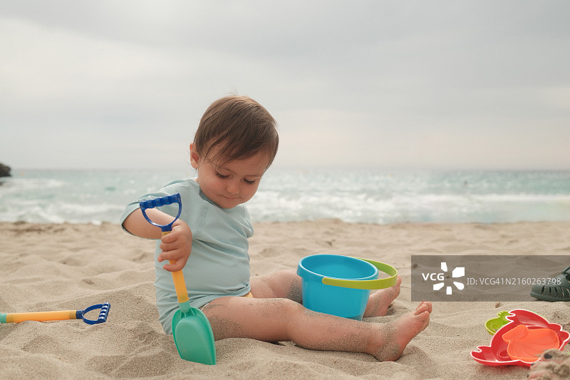 幼儿在海边沙滩上玩沙滩玩具图片素材