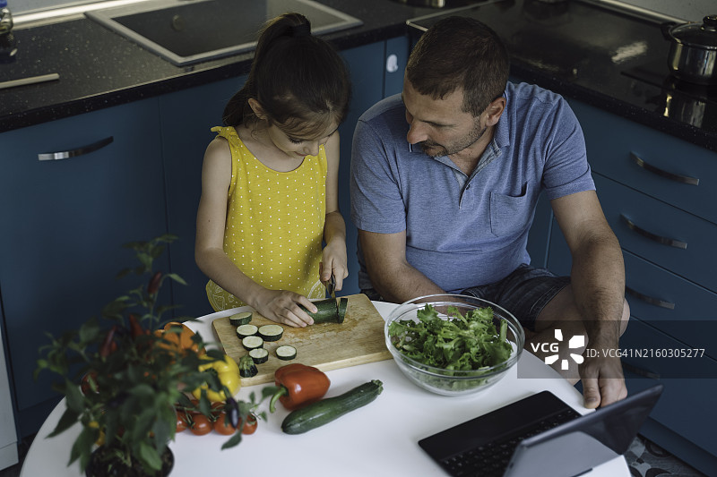 父女在餐桌旁一起切菜图片素材